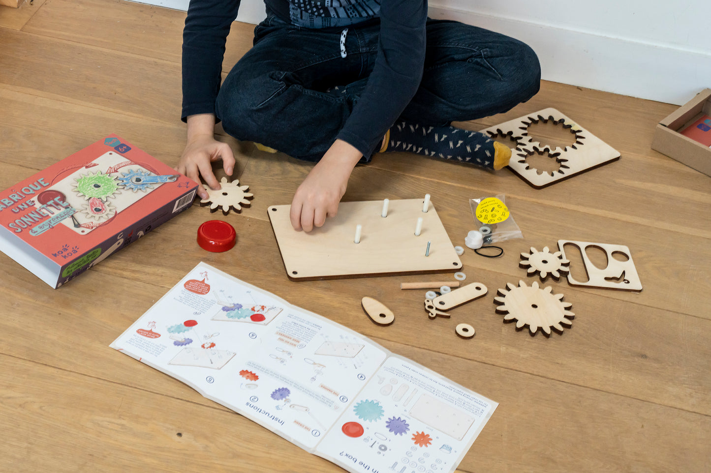 Different components of the Make Your Own Doorbell kit including gears, board and instruction manual