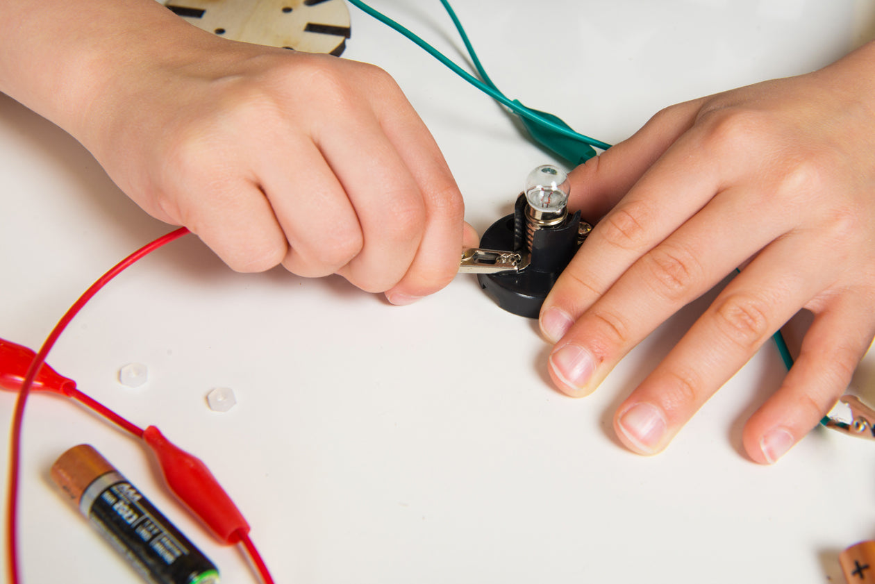 Child connecting wires to the light bulb in make your own flashlight kit