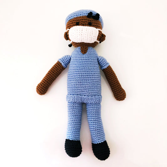 Dark-skinned doctor doll in blue scrubs and white mask