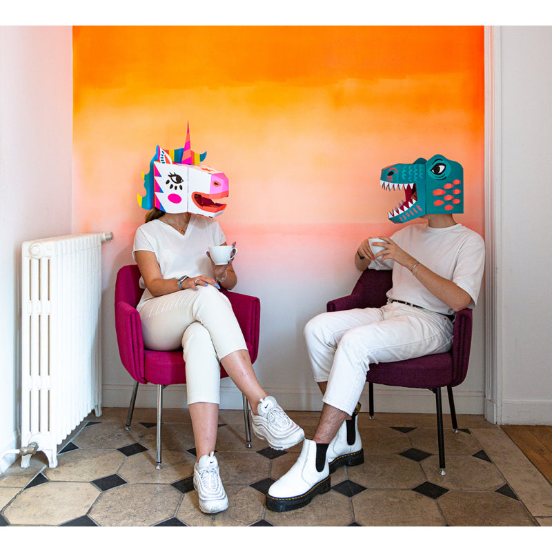 Man and woman in unicorn and dinosaur mask sipping tea