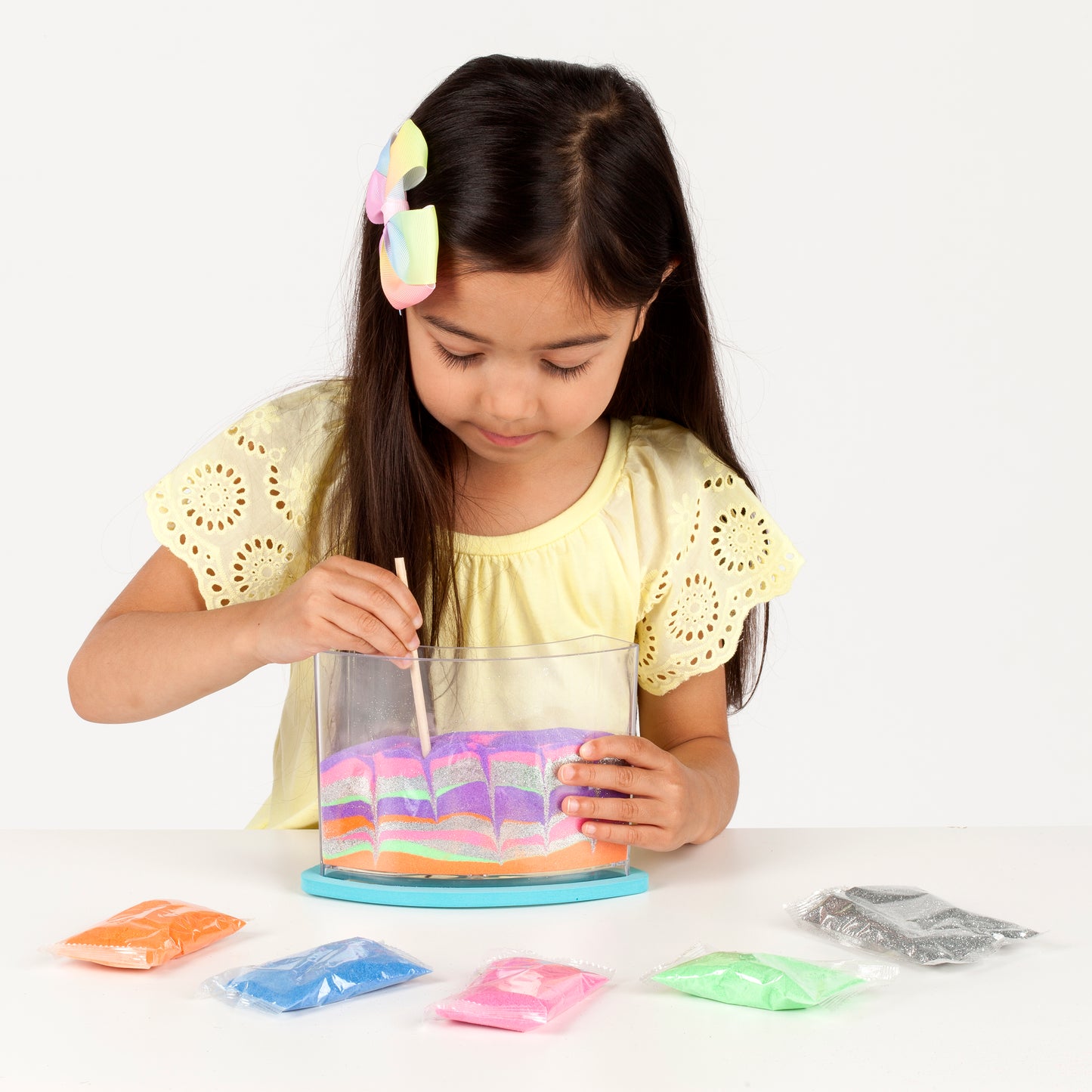 Little girl creating sand art with rainbow sandland kit from faber castell