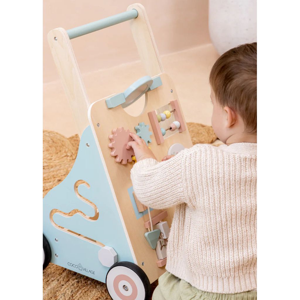 Toddler using Cocovillage walker with busy board