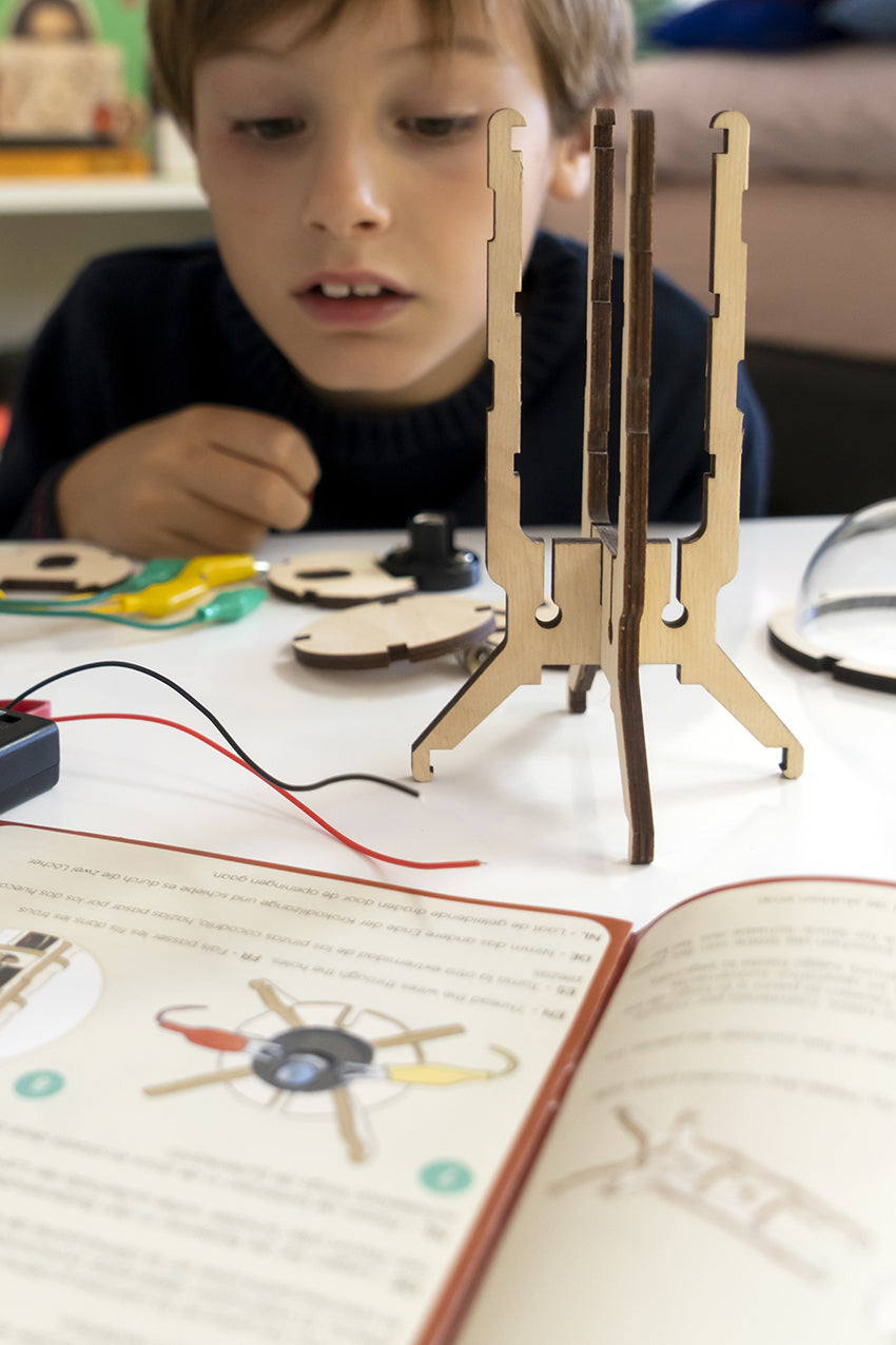 Child peering at the components of the make your own flashlight kit with opened instruction booklet