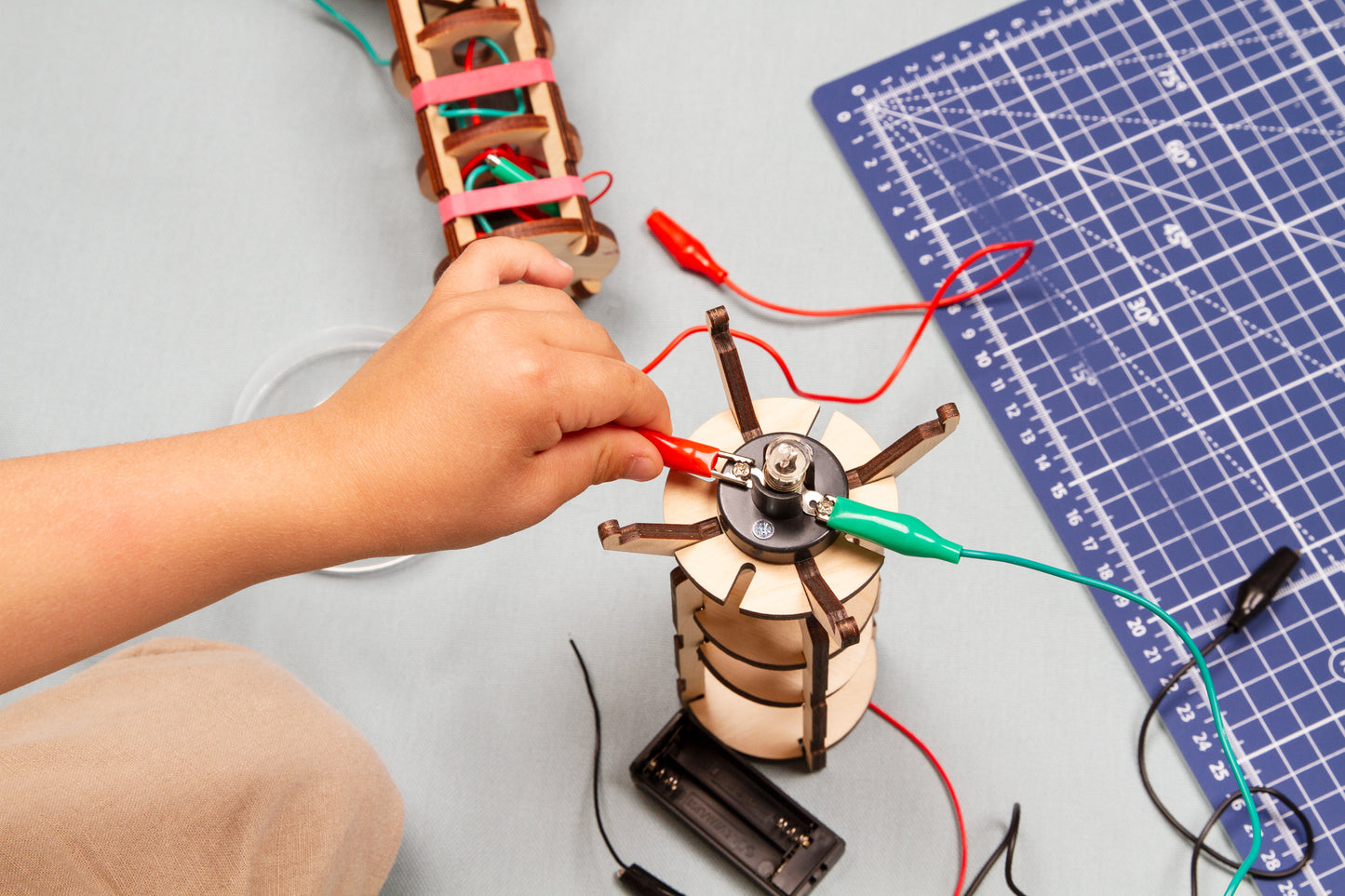 Child connecting wires to complete a circuit for the light bulb in make your own flashlight kit
