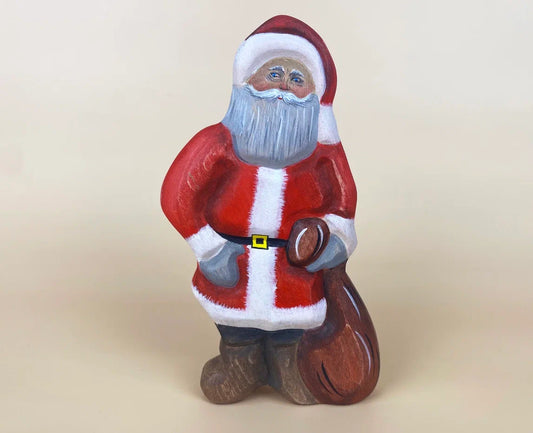 Wooden santa claus toy in red Christmas robes, Christmas hat and carrying a brown bag of presents! 