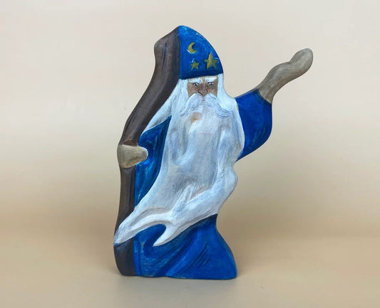 Wooden sorcerer figurine in blue hat, wielding a staff and casting a spell